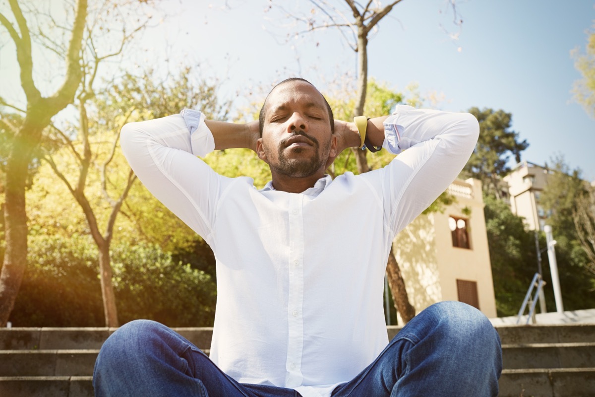 Man taking a deep breath on a park bench