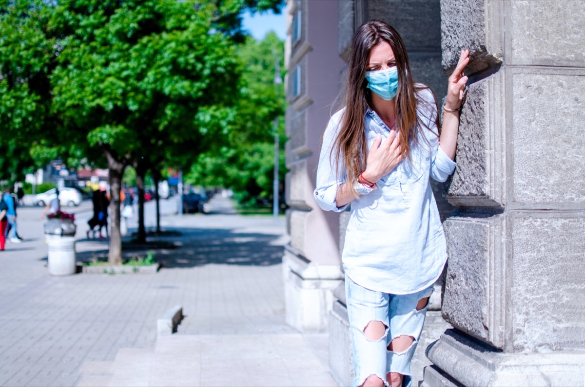 young woman outside clutching chest