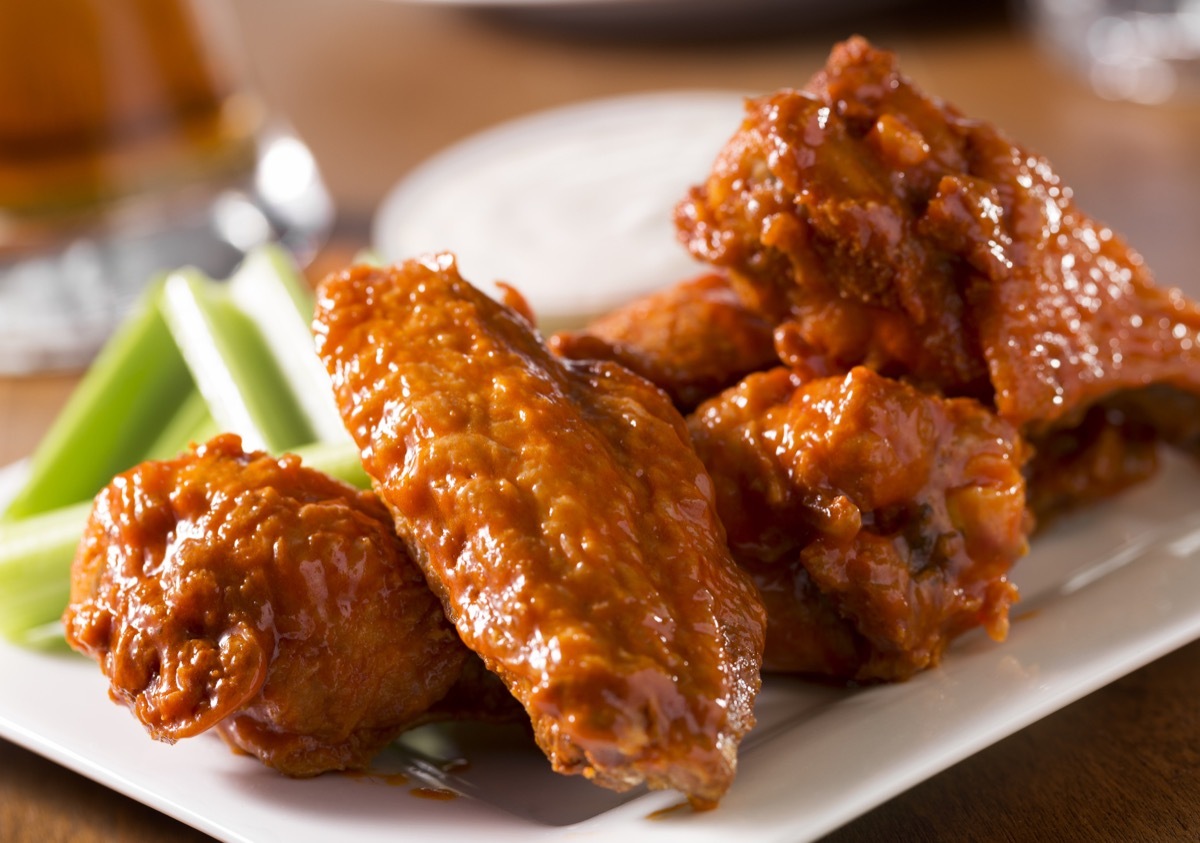 A plate of buffalo style chicken wings with celery and blue cheese with a beer on a bar or restaurant table. Please see my portfolio for other food and drink images.