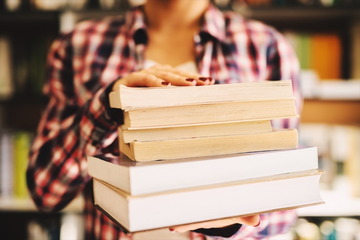 Close up of females hands holding books in front of the camera.