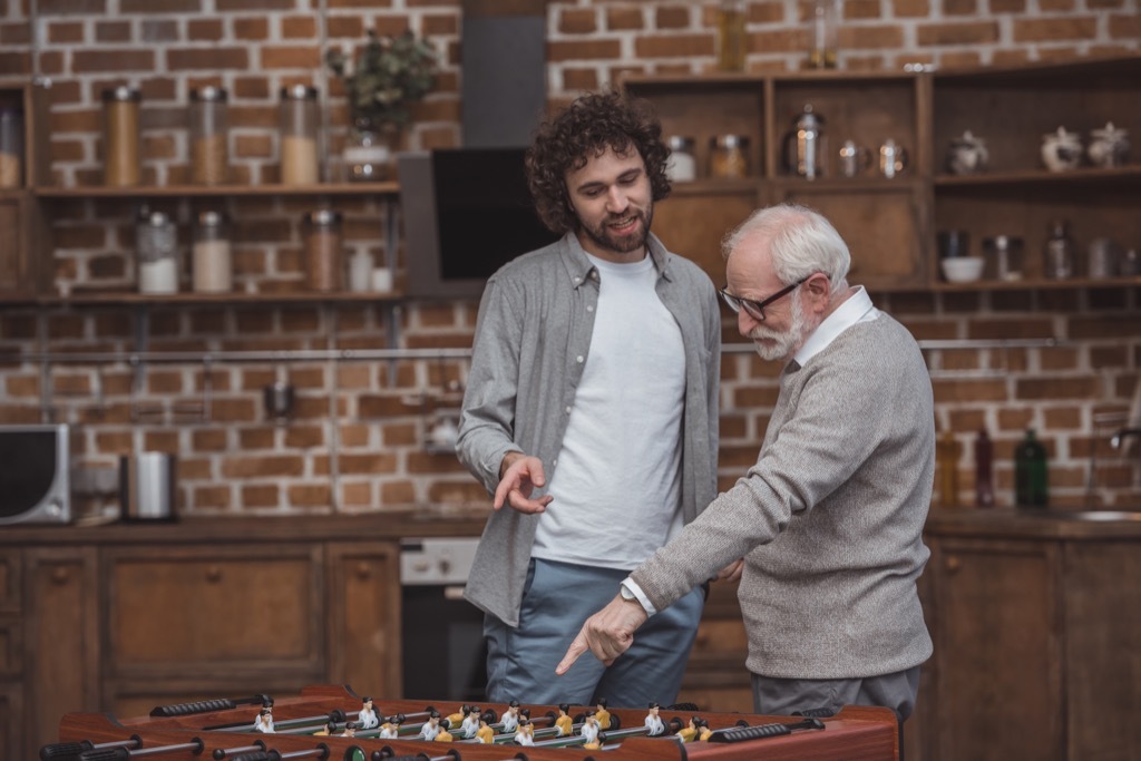 father and son pointing at table soccer game