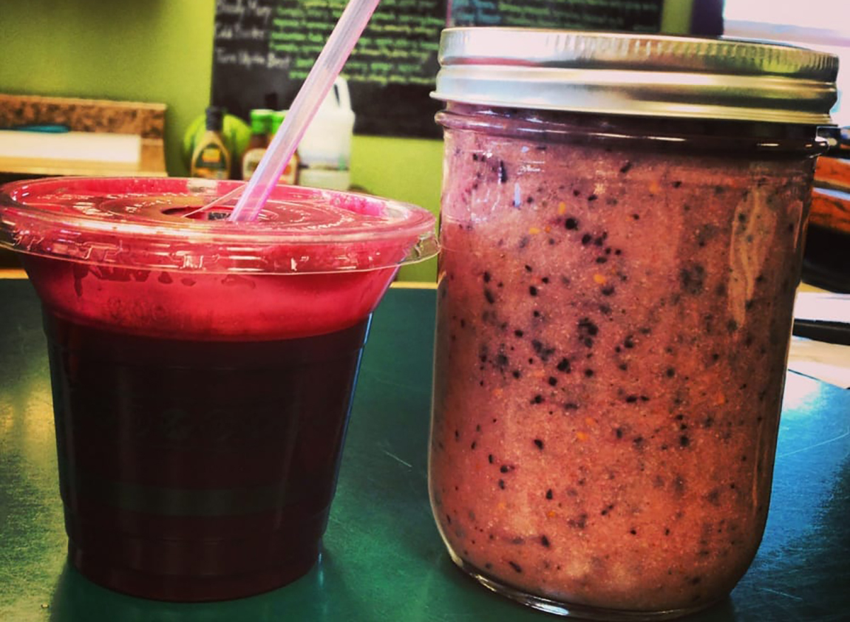 berry smoothie in plastic cup with second smoothie in mason jar