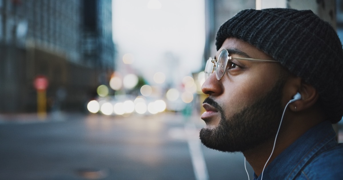 Shot of a young man listening to music in the city