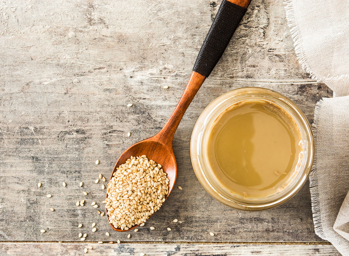 tahini in glass jar with wooden spoon