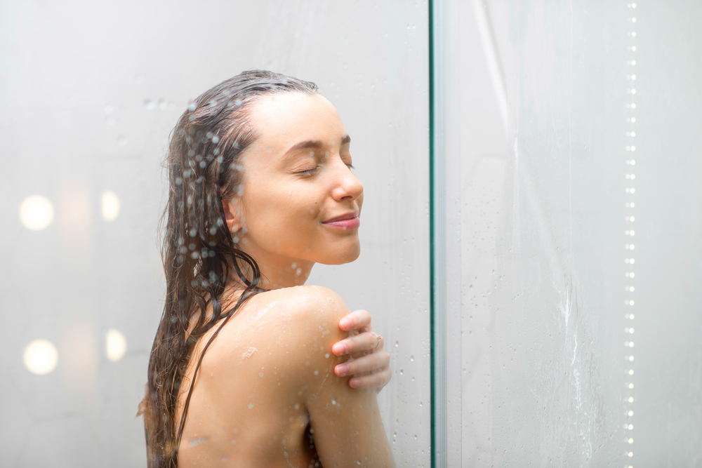 A young woman stands smiling in the shower