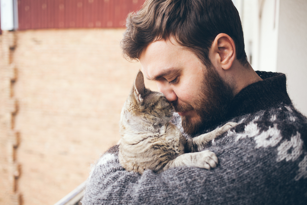 man cuddling his pet cat