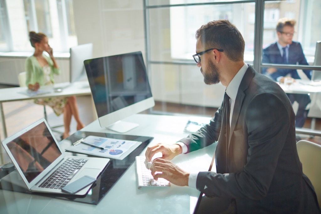 man typing on his computer at work