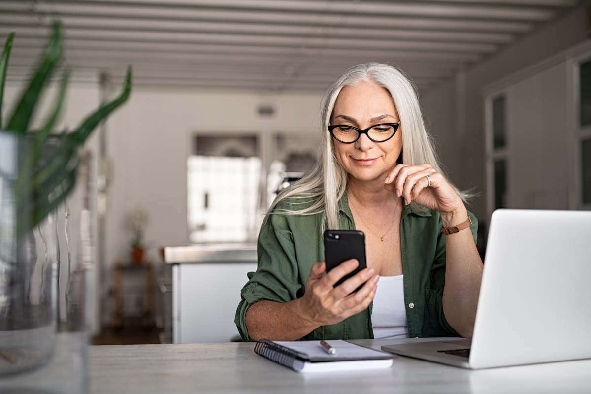 Older woman on phone with laptop next to her