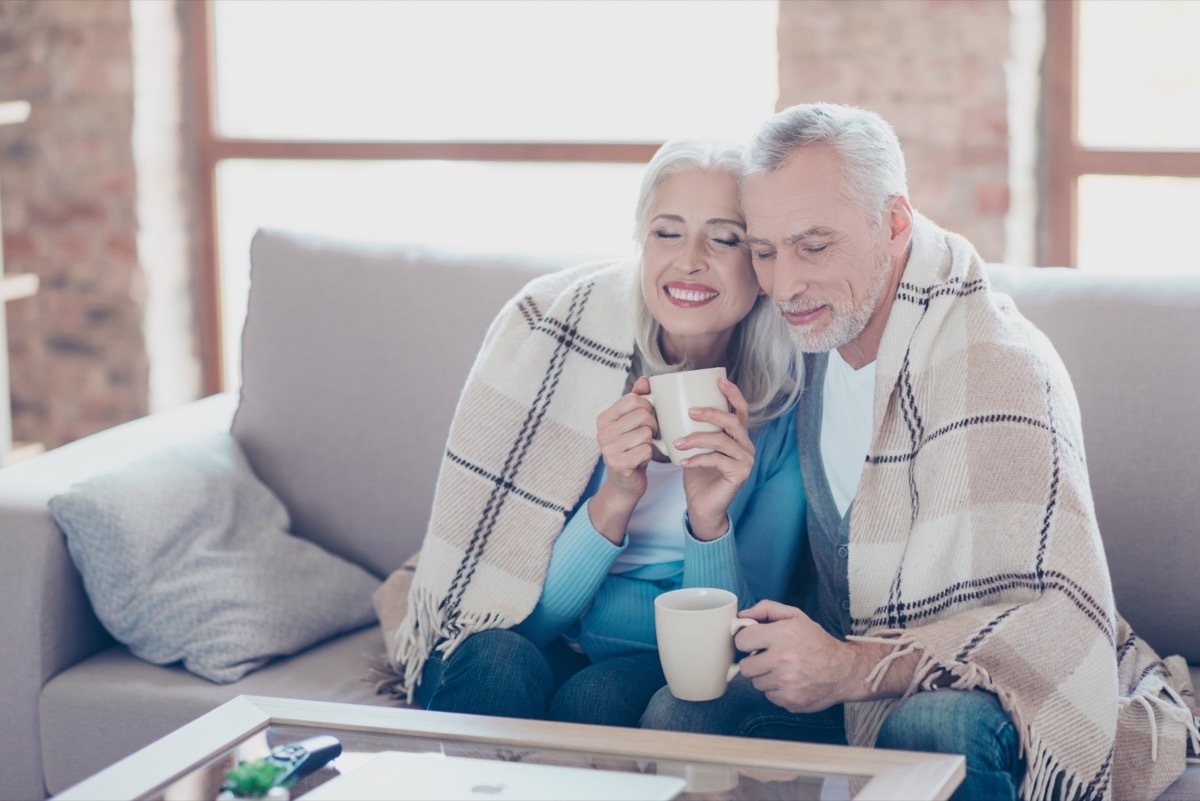 Older couple happily sitting under a blanket in the winter