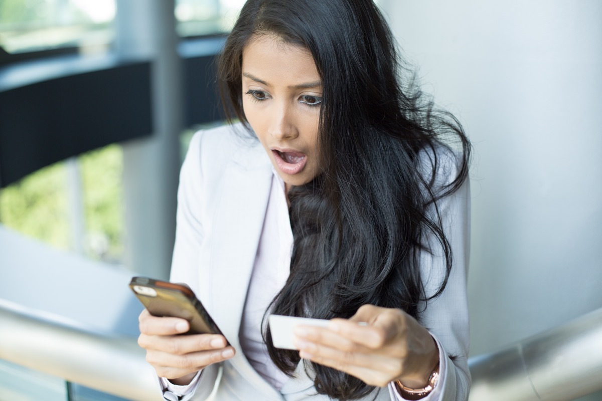 woman shocked looking at phone after winning the lottery