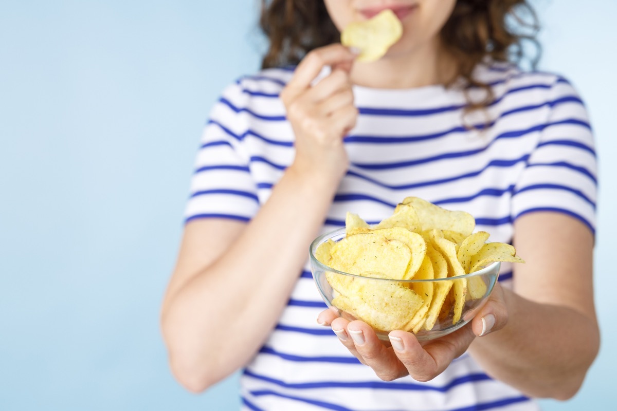 Young woman with chips on blue background