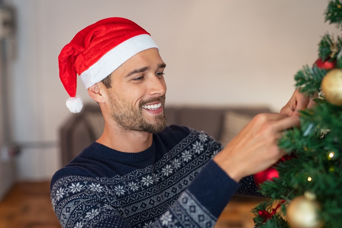 Man decorating a Christmas tree with ornaments