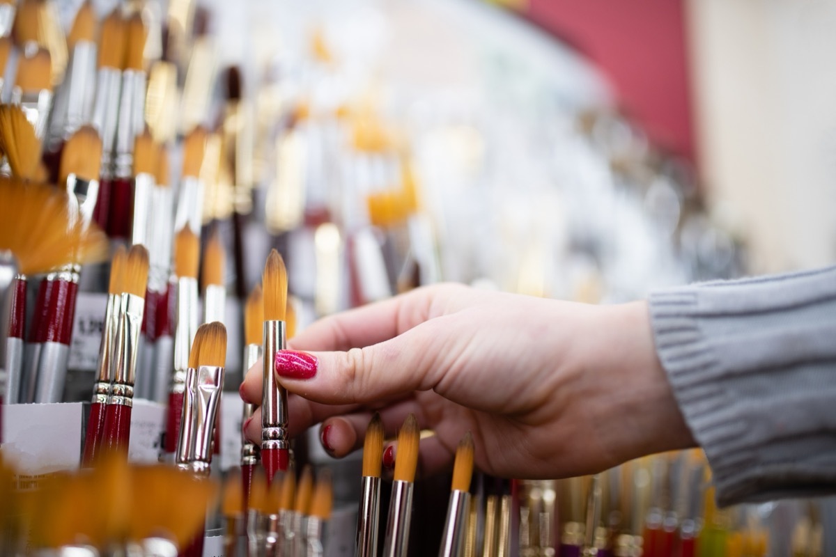 woman selecting paintbrush at store