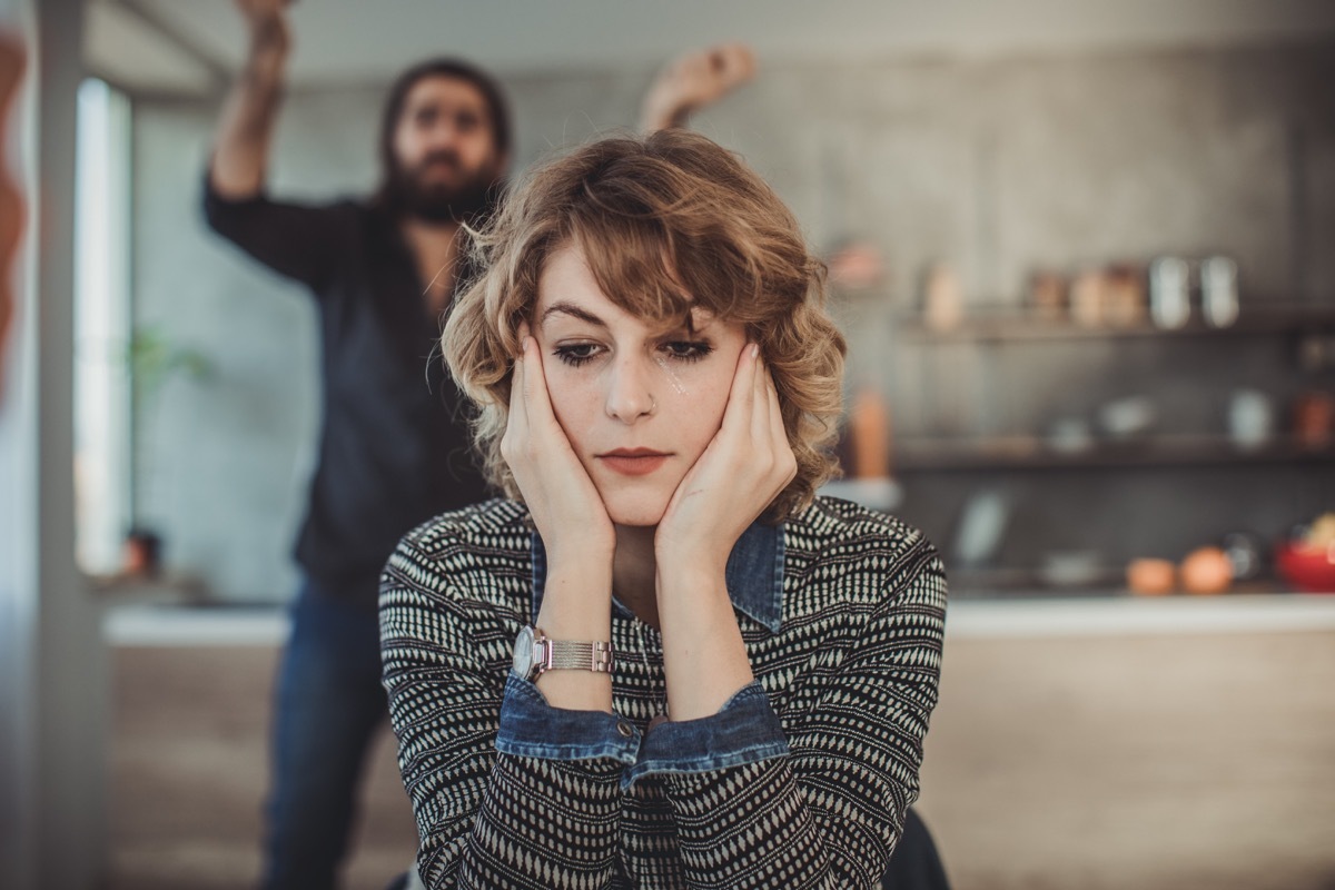 Furious couple arguing in the kitchen with sad woman