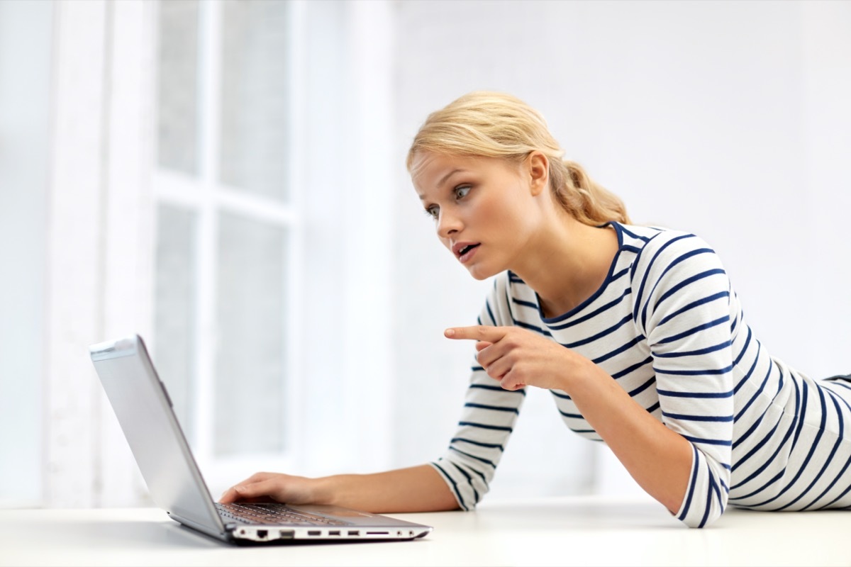 woman having video call and pointing finger to laptop computer at home