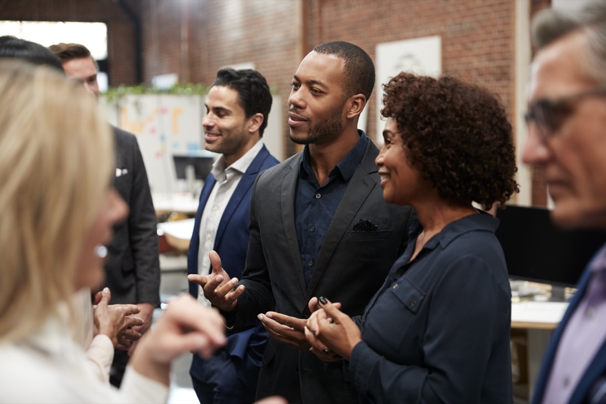 Business Team Standing Having Informal Meeting In Modern Office