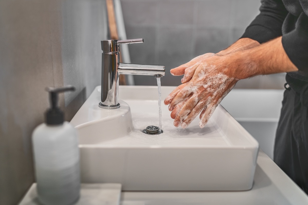 Washing hands with soap and hot water at home bathroom sink man cleansing hand hygiene