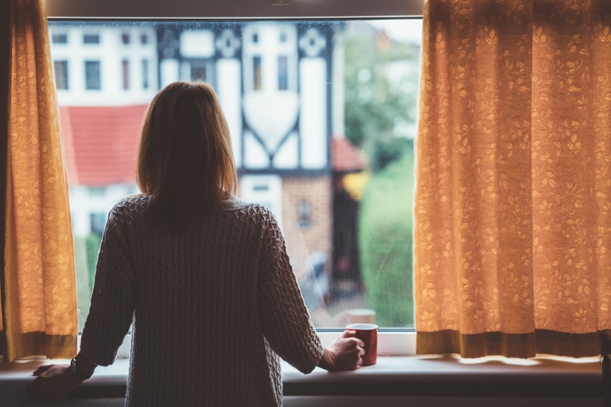 Rear view of woman at home staring through the window