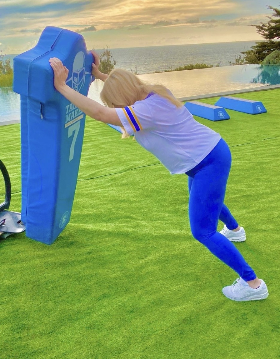 rebel wilson in blue pants and gray t-shirt pushing football barrier