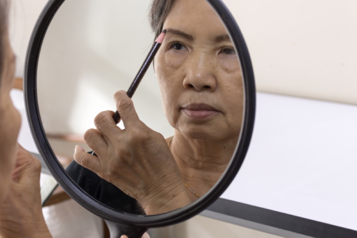 older woman applying eyebrow pencil, look better after 40