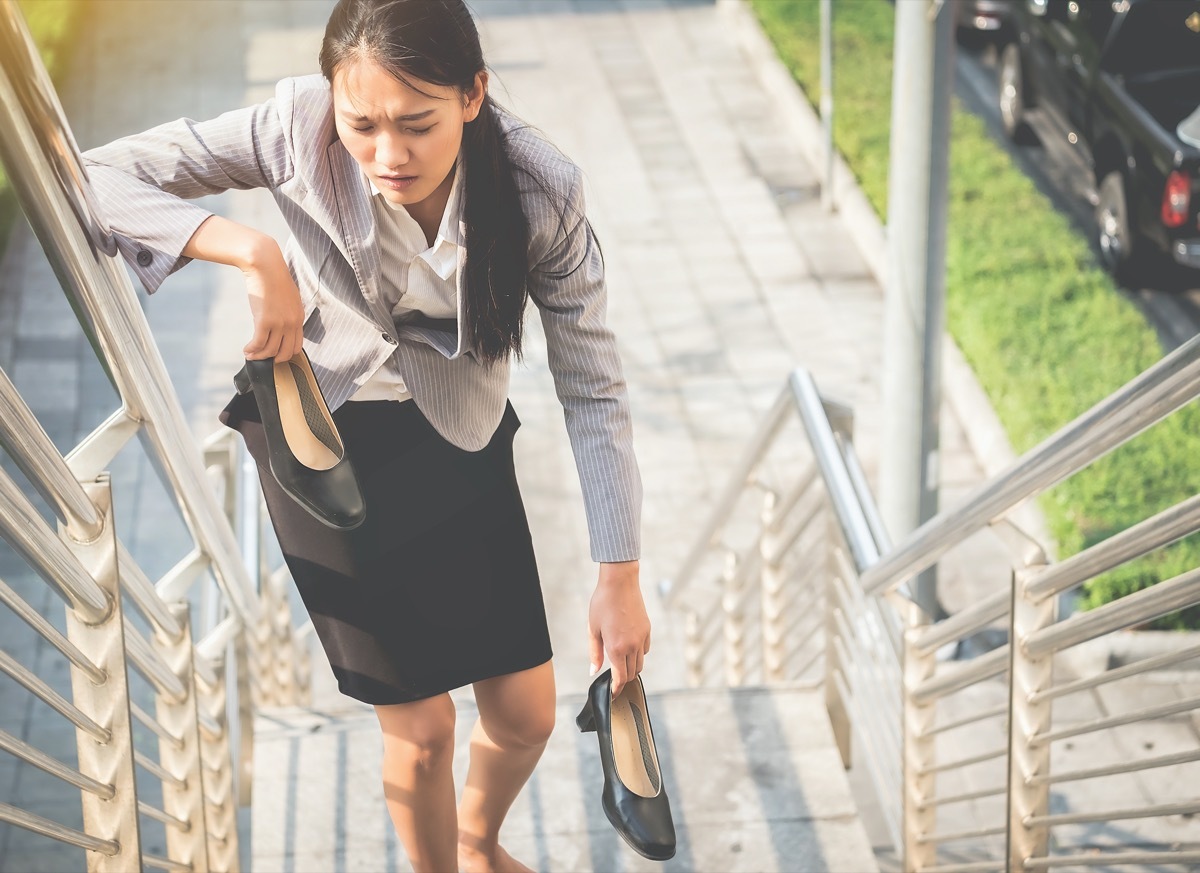 Women walk up the ladder with bare feet and Holding black high heels with fatigue