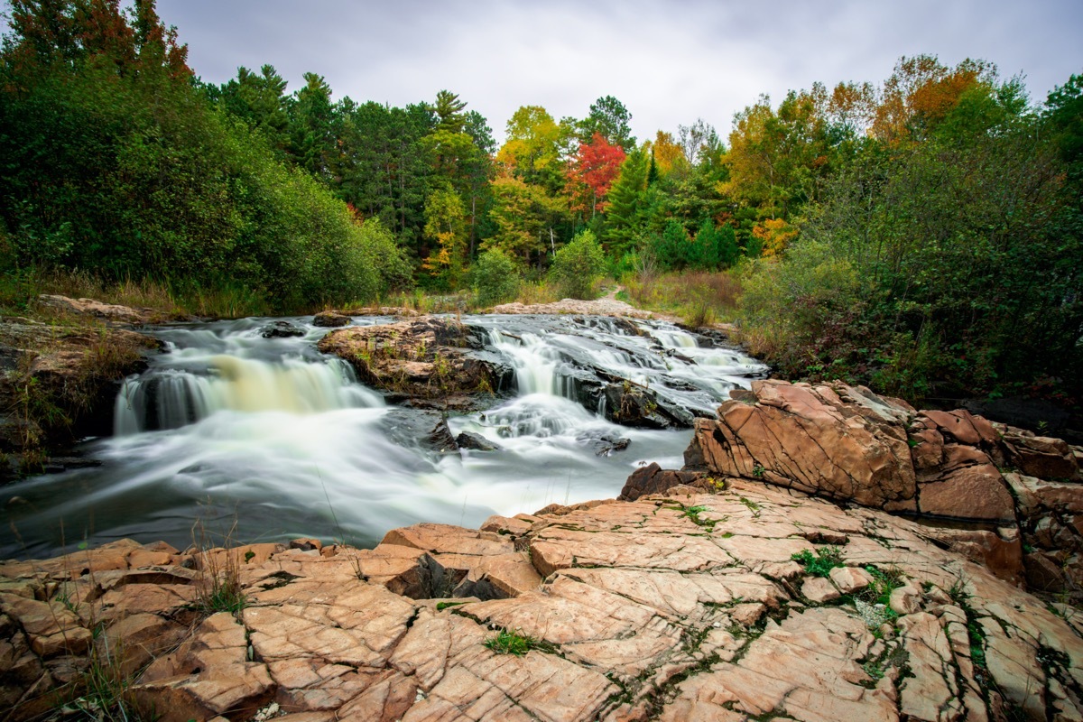 waterfall, green trees, and rocks in Marquette, Michigan