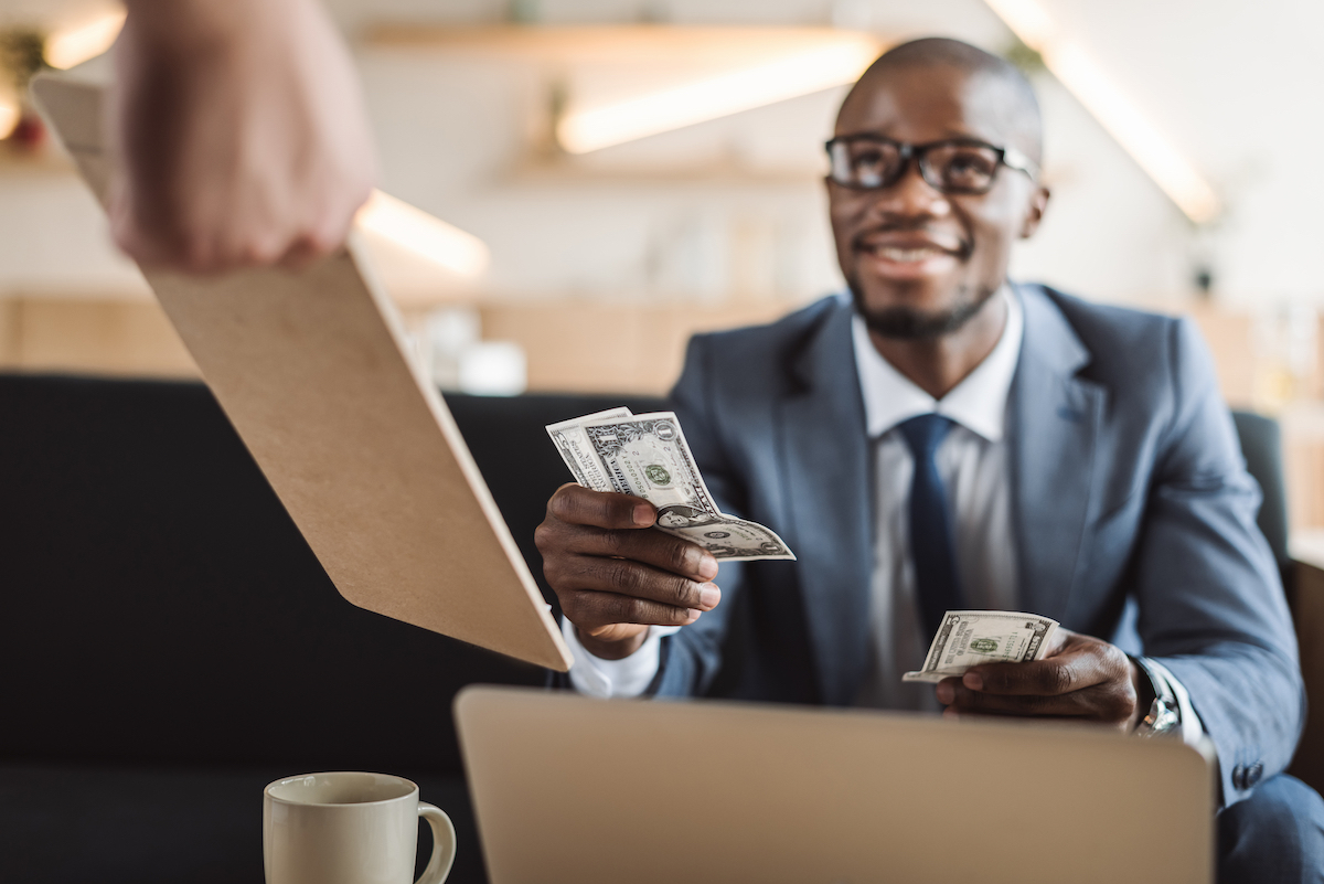 handsome businessman paying with cash in cafe