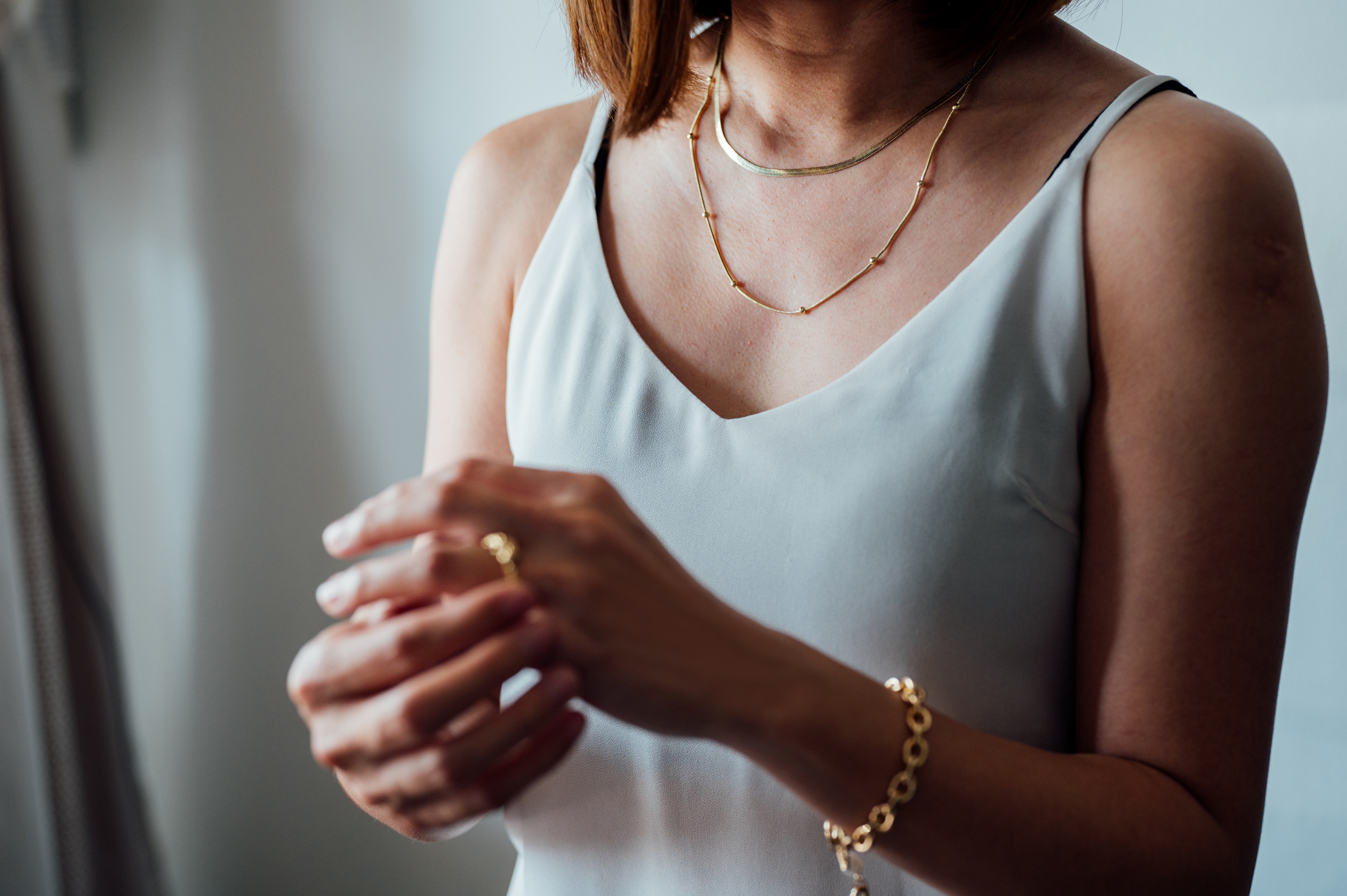 Close-up portrait of Asian woman dressed in a posh jewelry of gold ring, necklace and bracelet.