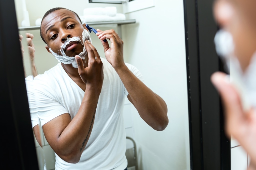 black man shaving in the mirror