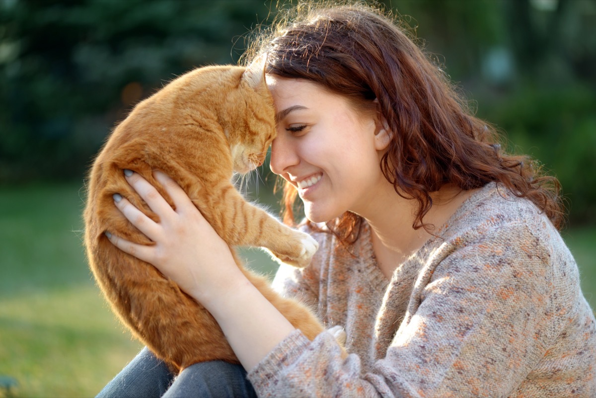 woman and cat playing in a green grass field