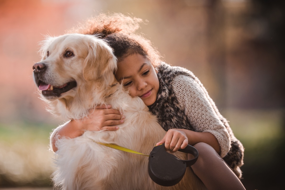 cute black girl embracing her retriever in nature.