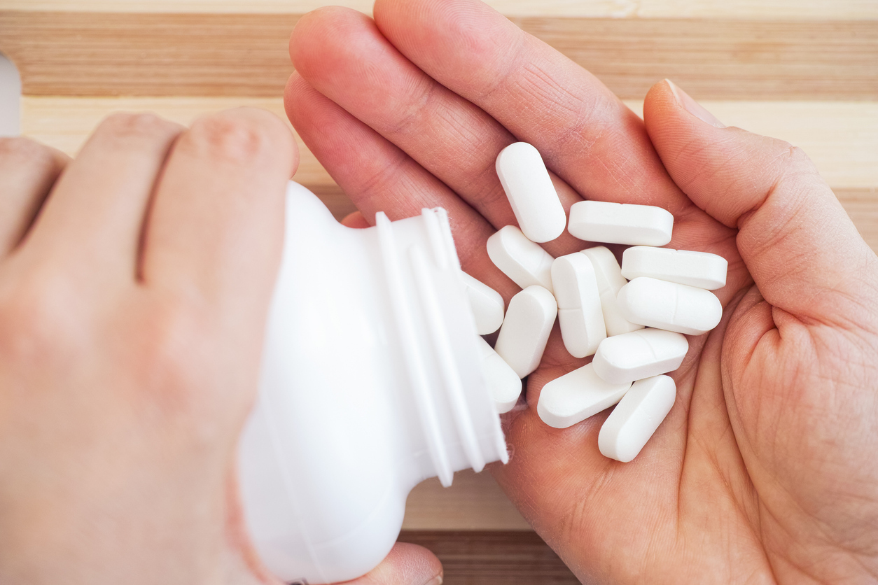 Woman taking magnesium pills out of a bottle. 