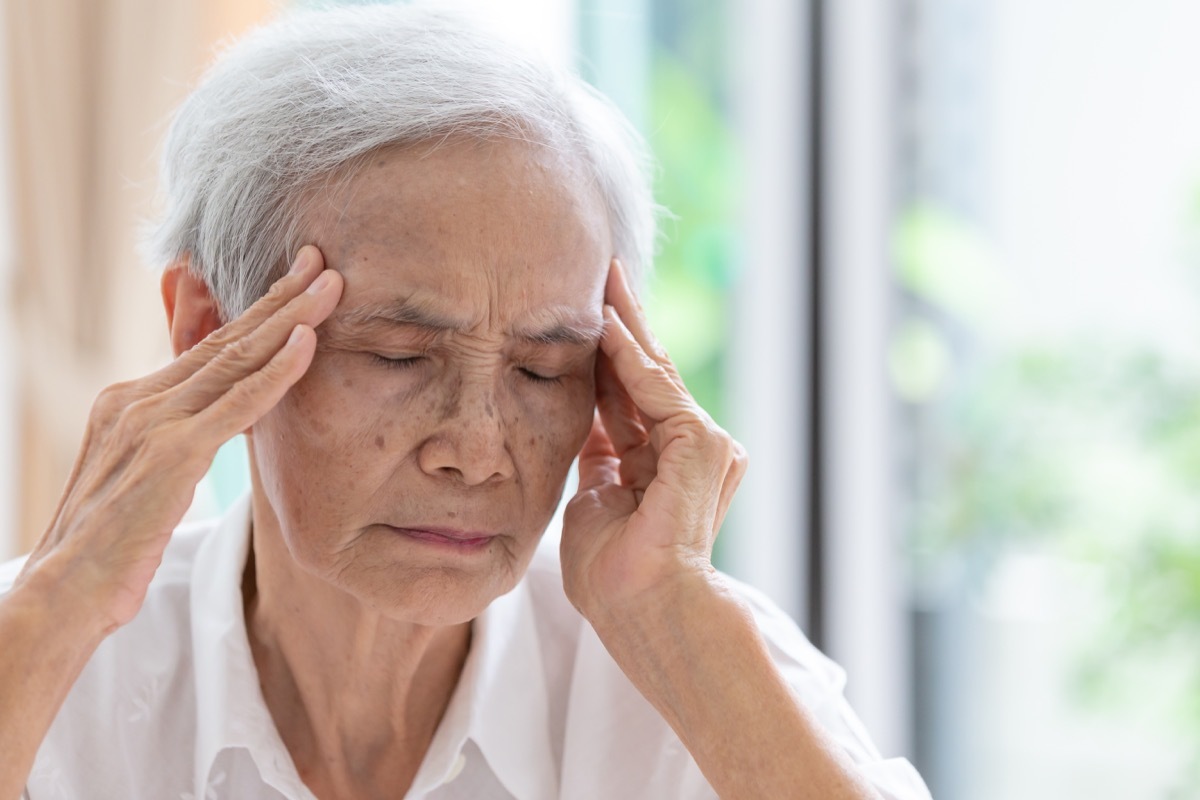 a woman with gray hair is experiencing a headache