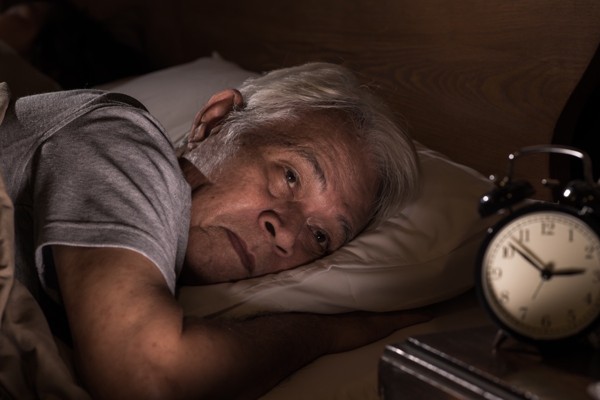 A depressed senior man lying in bed cannot sleep from insomnia