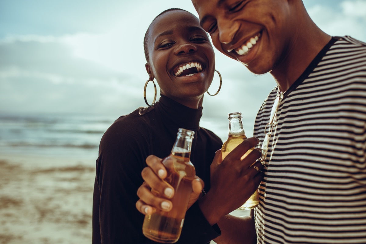 Couple drinking beer on the beach together