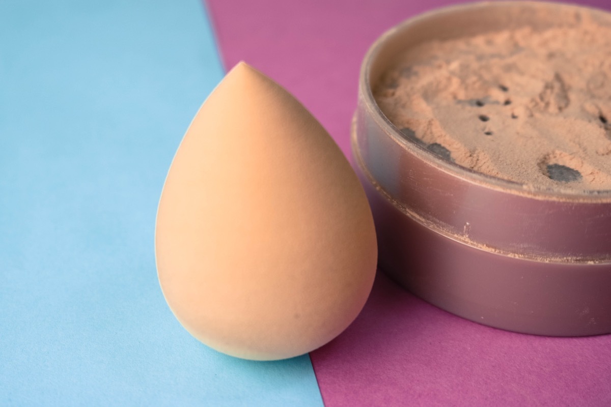 beauty box, set of female cosmetics, crumbly matte mineral powder and blush with a beauty blender for makeup on a blue pink and purple background. Flat lay. Top view.