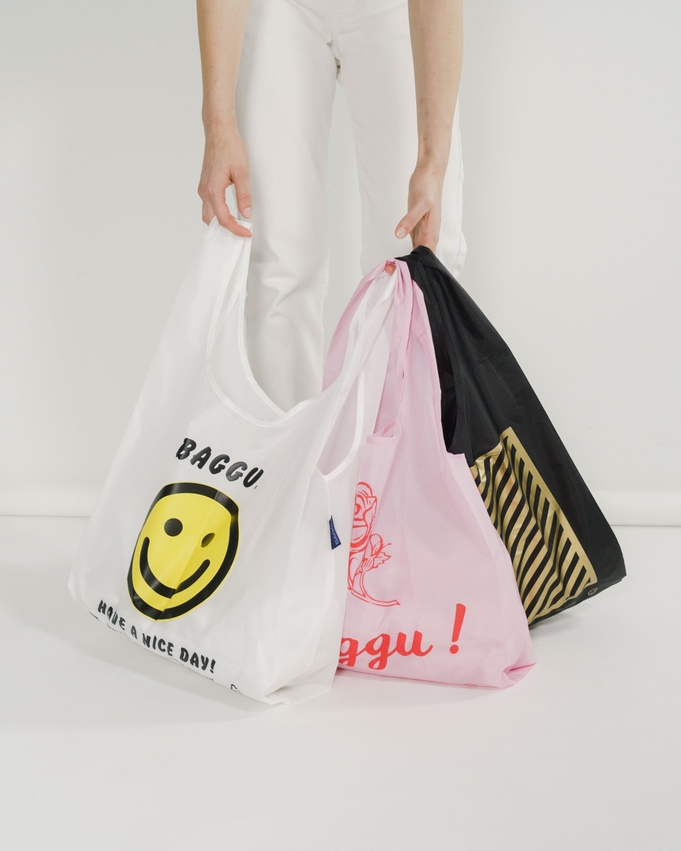 white hands holding reusable shopping bags