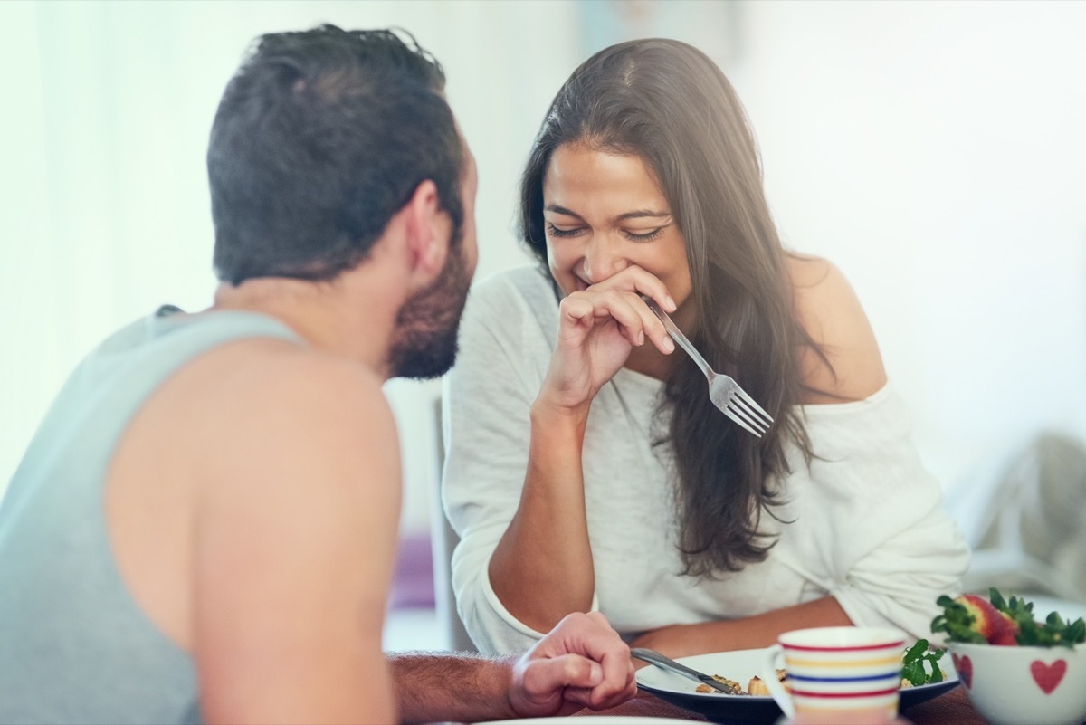 woman laughing as her husband tells her dad jokes