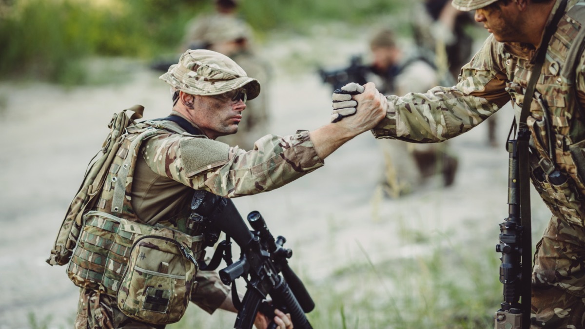 soldier pulling another soldier up by the hand