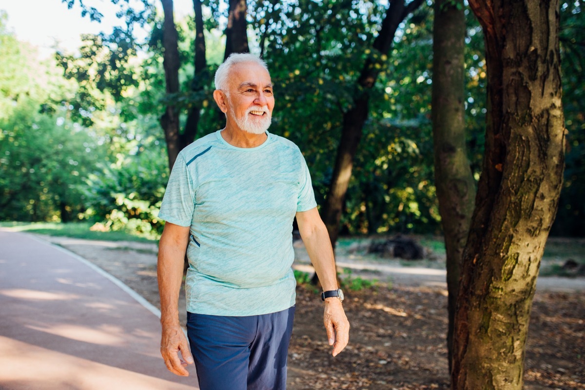 Senior man walking through the park after his running session.