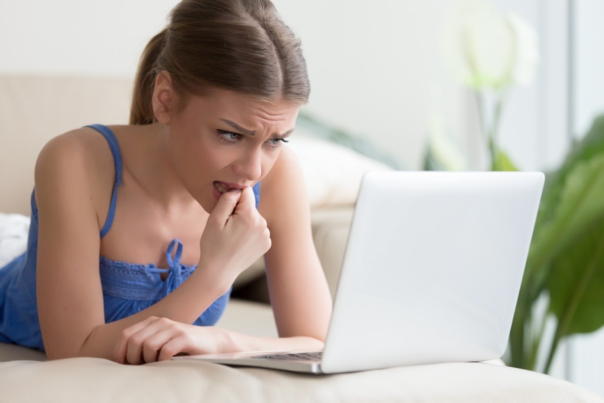 Girl biting nails on laptop