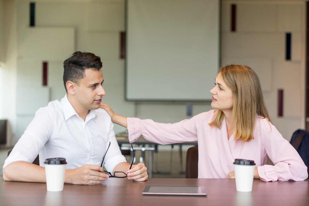 woman tapping male colleague on shoulder at coffee break.