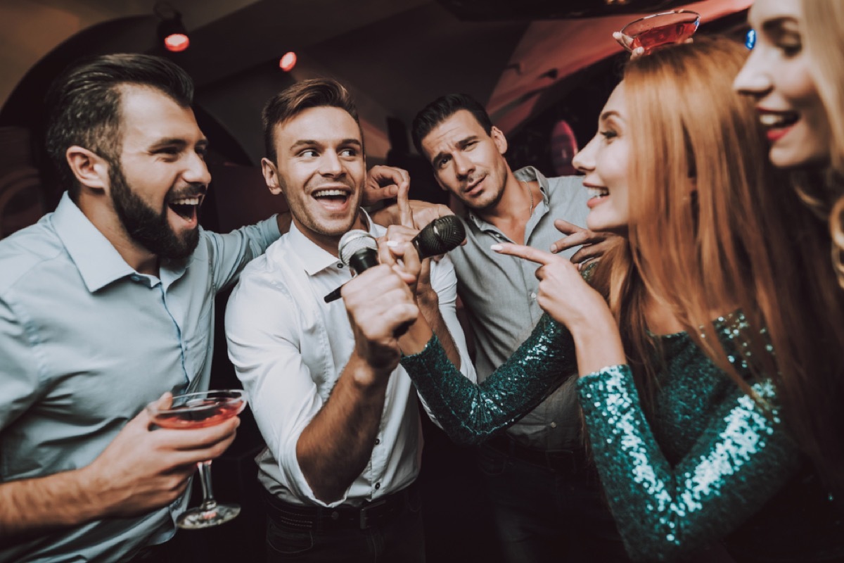 man singing karaoke while women watch, relationship white lies