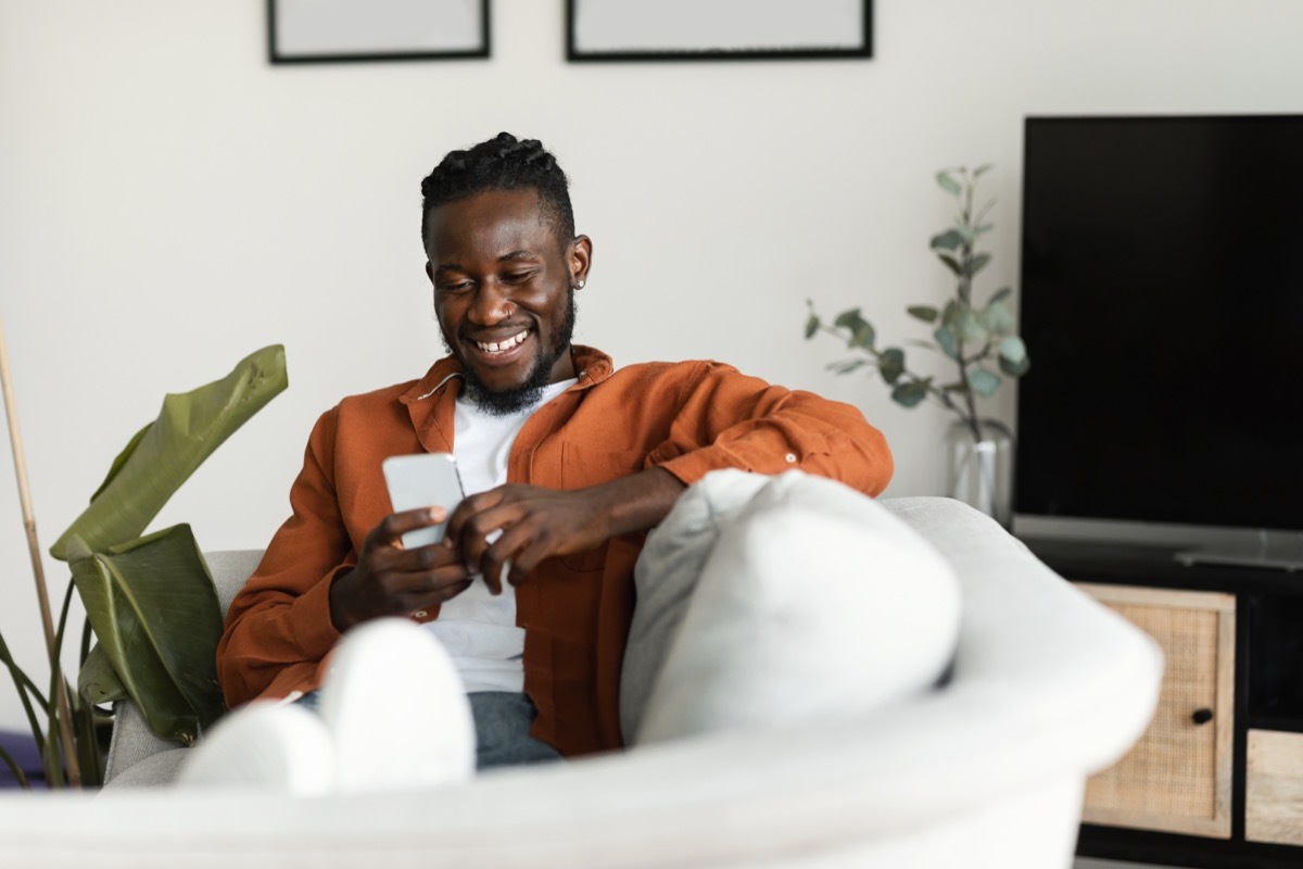 man smiling while looking at his phone