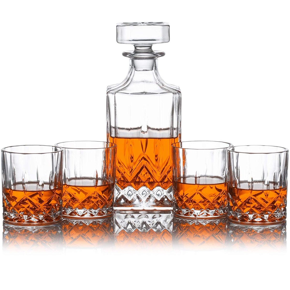 glass decanter and four cups with whiskey in them