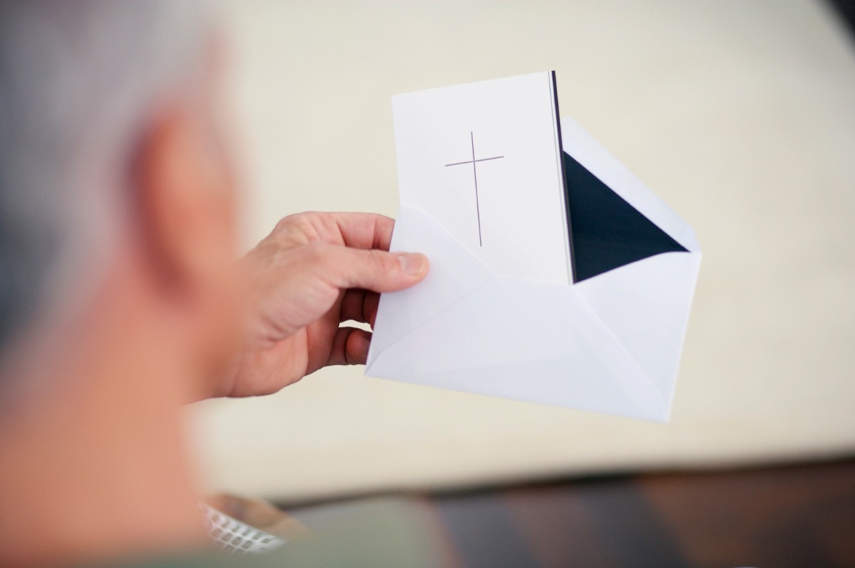 Detail of senior man holding condolence card at bereavement