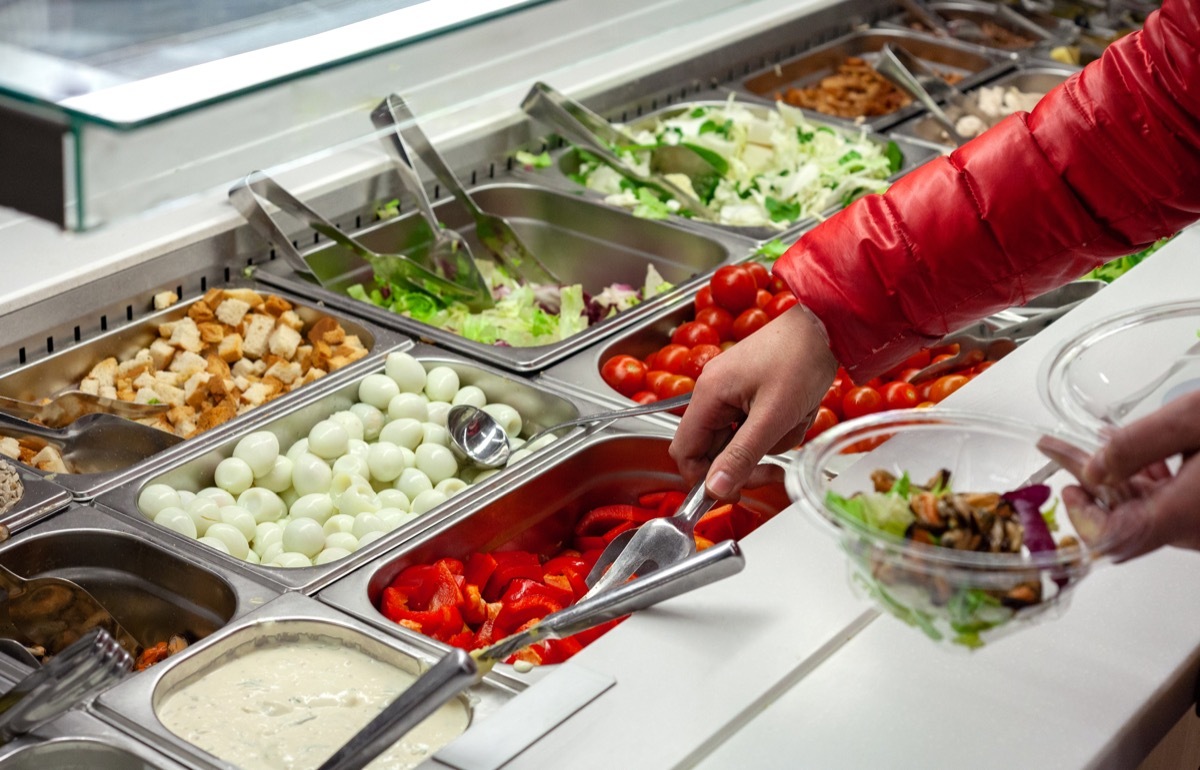 hand reaching into salad bar container