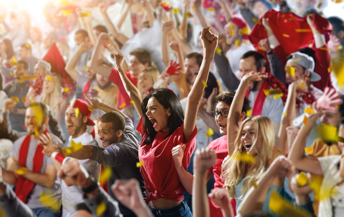 A group of Sport Fans cheering in the stands and wearing red for the team colors