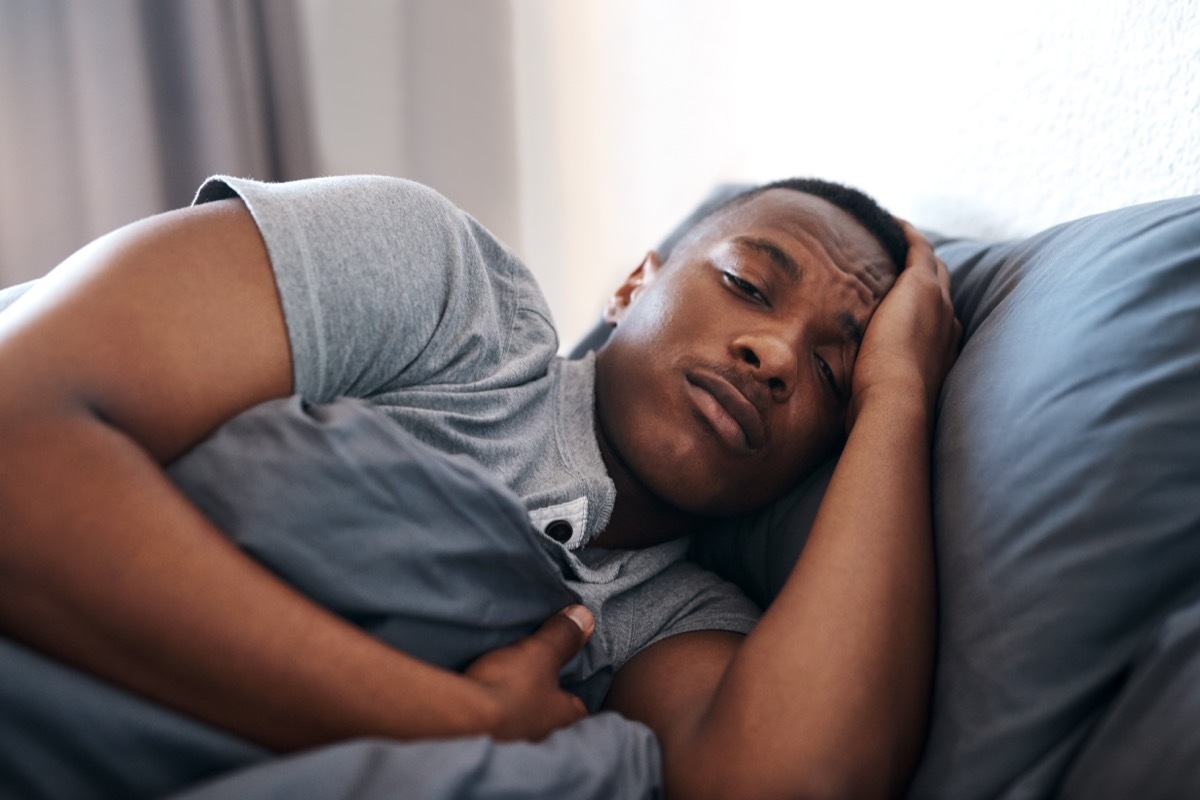 Cropped shot of a handsome young man lying in bed and feeling depressed while home alone