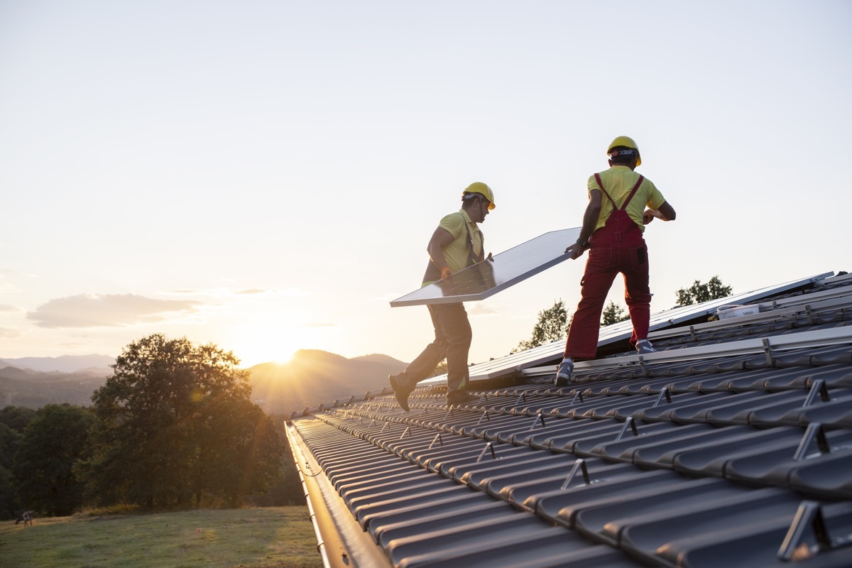 Shot of technicians installing solar panels on a roof.